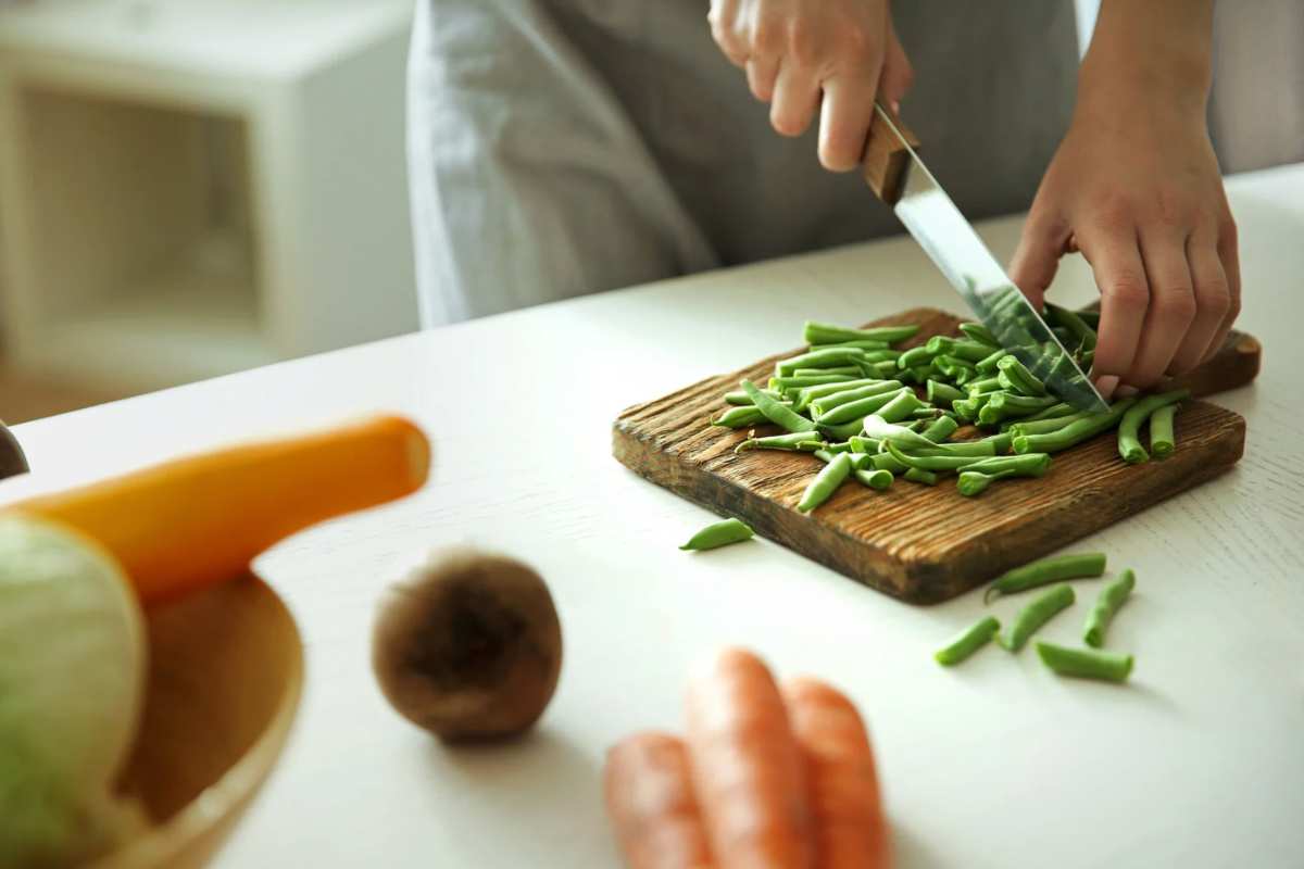 Persona che taglia verdure su un tagliere di legno