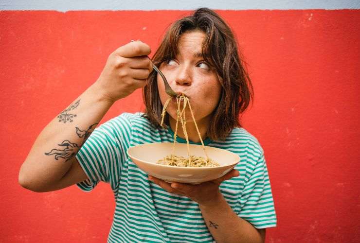 donna che mangia piatto di pasta 